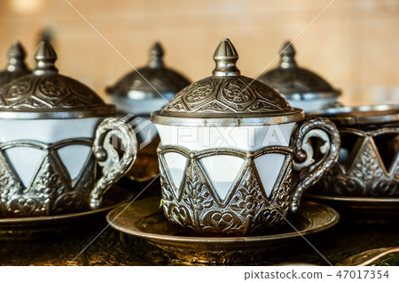 Covered coffee cup with metal decoration 47017354