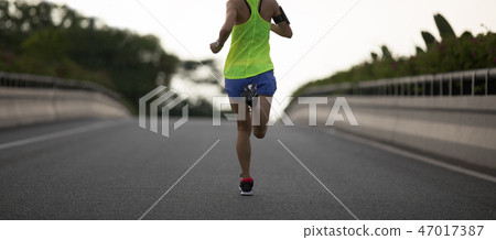 Young woman runner running on city road 47017387