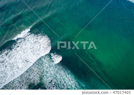 Aerial view of surfers paddling for catching waves Aerial view of surfers paddling for catching waves 47017405