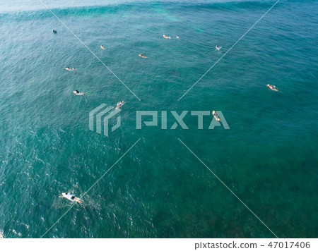 Aerial view of surfers paddling for catching waves Aerial view of surfers paddling for catching waves 47017406
