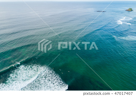 Aerial view of surfers paddling for catching waves Aerial view of surfers paddling for catching waves 47017407