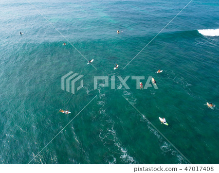 Aerial view of surfers paddling for catching waves Aerial view of surfers paddling for catching waves 47017408