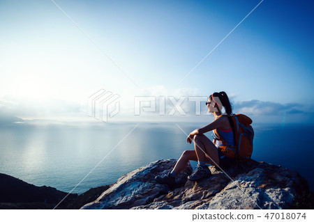 young woman hiker at sunrise seaside mountain peak 47018074