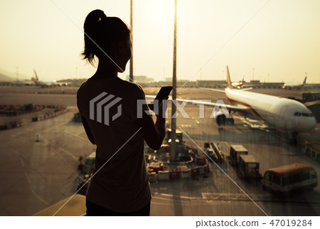 Woman  passenger using mobile phone in airport 47019284