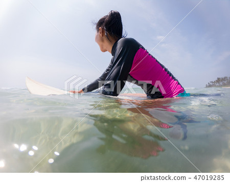 woman in swimming suit resting on surfing board  47019285