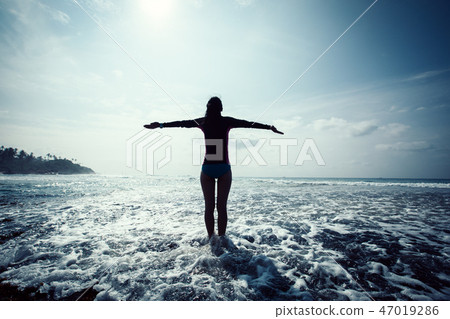 Woman outstretched arms at Sunrise seaside reef 47019286
