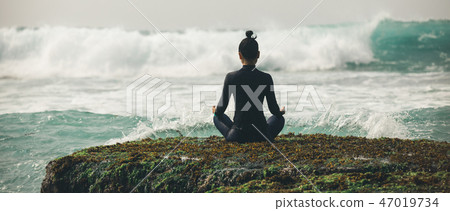 Yoga woman meditation at the seaside cliff edge  47019734