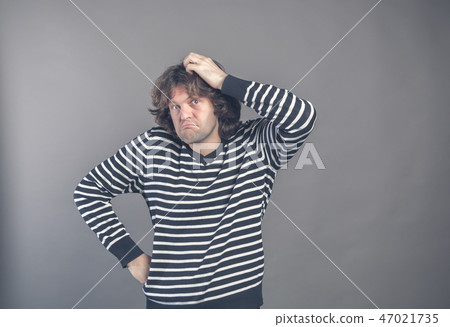 Puzzled guy with messy hair, frowning and looking unsatisfied scratching head, thinking deeply about 47021735