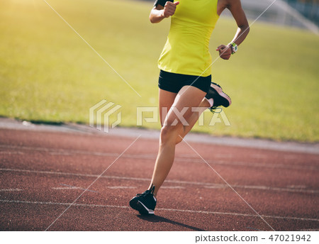 Fitness sportswoman running on stadium tracks 47021942