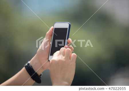 Hands using smartphone in modern city 47022035