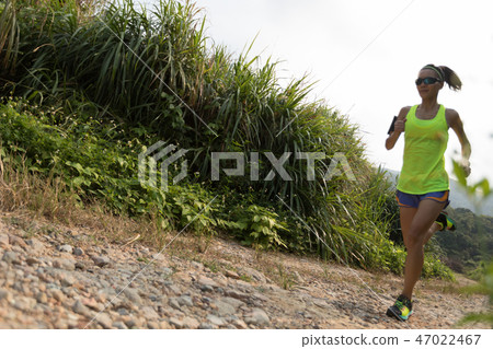 young fitness woman trail runner running on rocky mountain trail 47022467