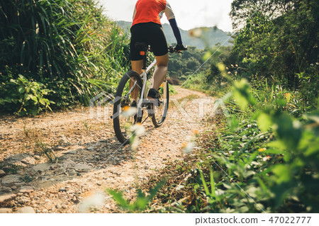 Woman cyclist riding mountain bike on rocky trail  47022777