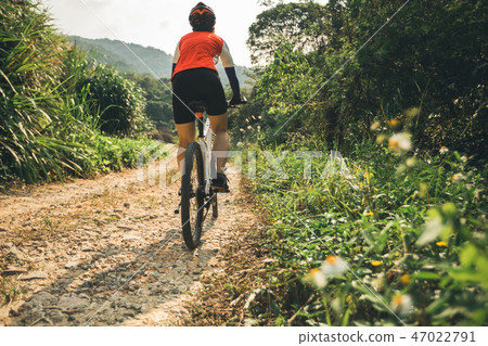 Woman cyclist riding mountain bike on rocky trail Woman cyclist riding mountain bike on rocky trail 47022791
