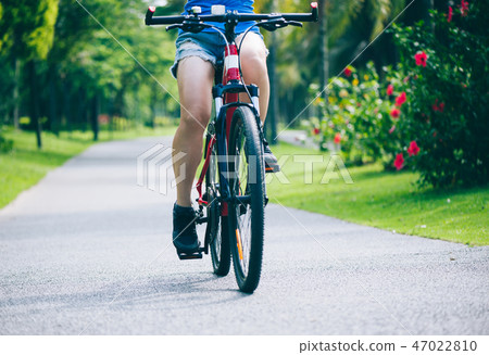 Woman riding mountain bike in tropical park 47022810