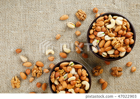 Mix of various nuts in a wooden cup against Mix of various nuts in a wooden cup against 47022903