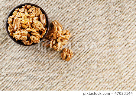 Peeled walnuts in a wooden, dark brown cup Peeled walnuts in a wooden, dark brown cup 47023144