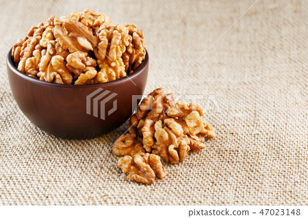 Peeled walnuts in a wooden, dark brown cup Peeled walnuts in a wooden, dark brown cup 47023148
