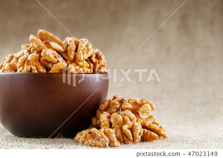 Peeled walnuts in a wooden, dark brown cup Peeled walnuts in a wooden, dark brown cup 47023149