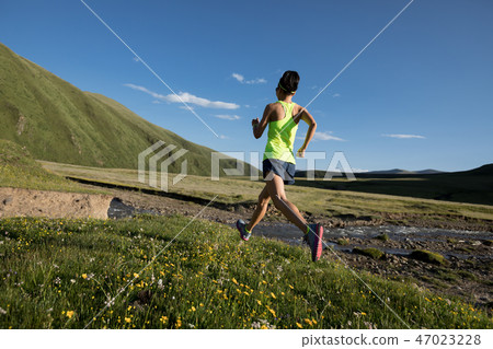 fitness woman trail runner running on grassland 47023228