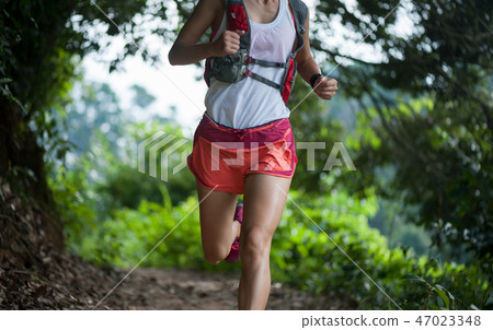 Young woman trail runner running on  forest trail 47023348
