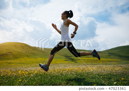Young fitness woman trail runner running grassland 47023361