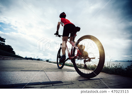 cyclist riding Mountain Bike on sunrise seaside 47023515