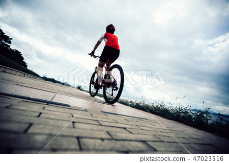 Woman cyclist riding Mountain Bike on seaside 47023516