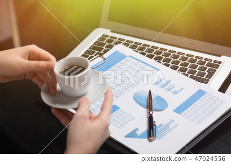 Businesswoman holding mug of coffee and acquainted with diagrams 47024556