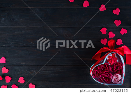 Valentines background with red hearts shaped and bouquet rose in gift box on dark wooden background Valentines background with red hearts shaped and bouquet rose in gift box on dark wooden background 47028155