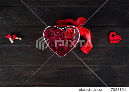 Valentines background with red hearts shaped and bouquet rose in gift box on dark wooden background Valentines background with red hearts shaped and bouquet rose in gift box on dark wooden background 47028164