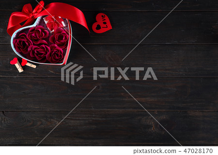 Valentines background with red hearts shaped and bouquet rose in gift box on dark wooden background Valentines background with red hearts shaped and bouquet rose in gift box on dark wooden background 47028170