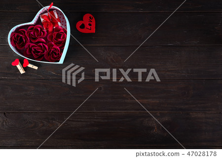 Valentines background with red hearts shaped and bouquet rose in gift box on dark wooden background Valentines background with red hearts shaped and bouquet rose in gift box on dark wooden background 47028178