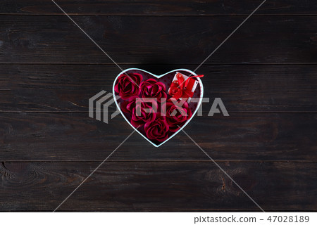 Valentines background with red hearts shaped and bouquet rose in gift box on dark wooden background Valentines background with red hearts shaped and bouquet rose in gift box on dark wooden background 47028189