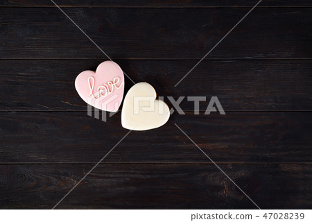 Sweets on Valentine's Day. Cookies in shape of heart and with lettering Love on dark wooden 47028239