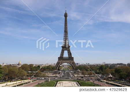 Eiffel Tower and there are a lot of tourists, cars and trees near it 47029629