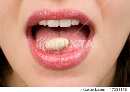 Woman takes pills on tongue 47031188