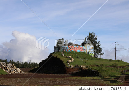 Building stands on high ground and painted with multicolored cans 47032844