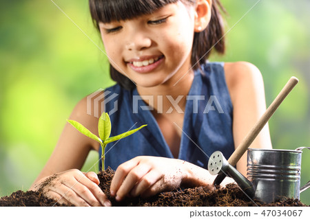 A girl planting young plant on soil with a hope A girl planting young plant on soil with a hope 47034067