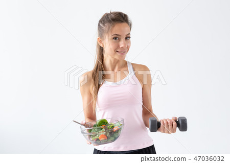 Healthy lifestyle, diet, fitness and people concept - young woman is eating a salad and doing sport 47036032