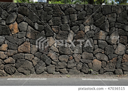 Stone fence separating the roadway and building 47036515