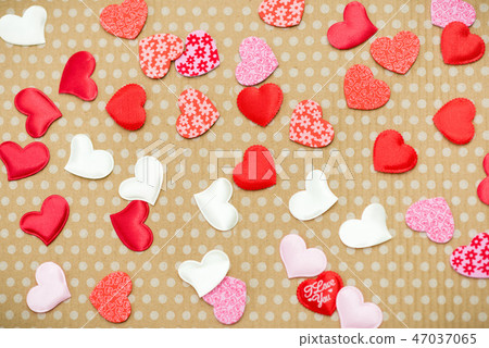 Many red hearts lie on an old cardboard background in white peas. Many red hearts lie on an old cardboard background in white peas. 47037065