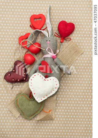 Rabbit handmade with red and white hearts lying on cardboard background in white peas Rabbit handmade with red and white hearts lying on cardboard background in white peas 47037095