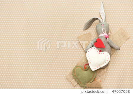 Rabbit handmade with red and white hearts lying on cardboard background in white peas Rabbit handmade with red and white hearts lying on cardboard background in white peas 47037098