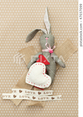 Rabbit handmade with red and white hearts lying on cardboard background in white peas Rabbit handmade with red and white hearts lying on cardboard background in white peas 47037099