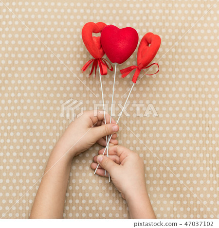 The child is holding red hearts on sticks 47037102