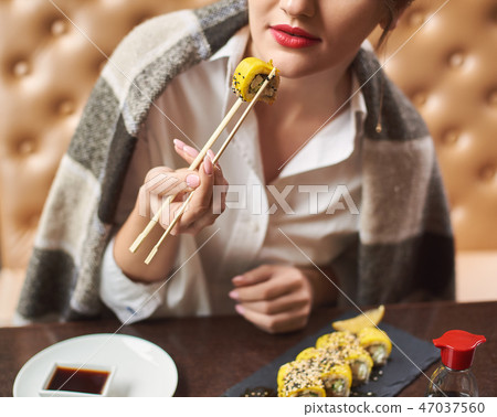 Girl enjoying asian dish with soy sauce using food sticks. 47037560