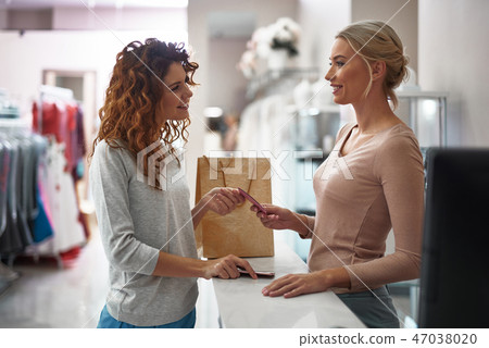 Young smiling lady giving credit card on register 47038020