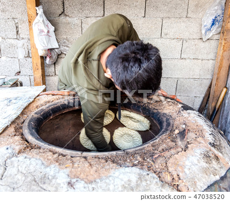 Traditional Uzbek flatbread baking in the tandir Traditional Uzbek flatbread baking in the tandir 47038520