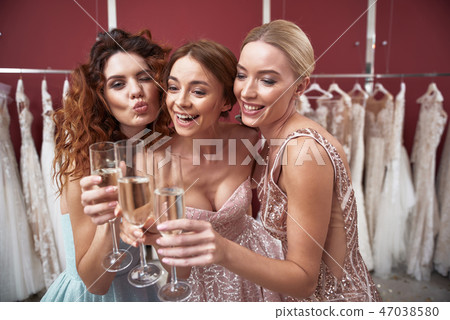 Three smiling ladies clanging of champagne glasses Three smiling ladies clanging of champagne glasses 47038580