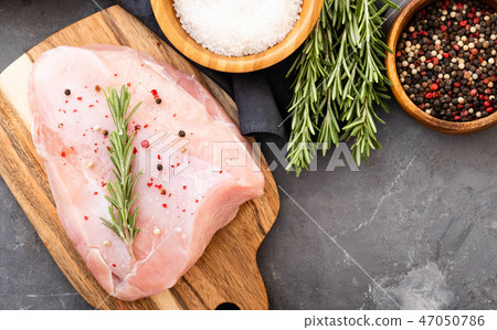 Raw turkey fillets on black cutting board with spices and herbs. Cooking ingredients. Natural Raw turkey fillets on black cutting board with spices and herbs. Cooking ingredients. Natural 47050786